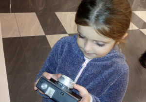 Dziewczynka ogląda stary aparat fotograficzny.